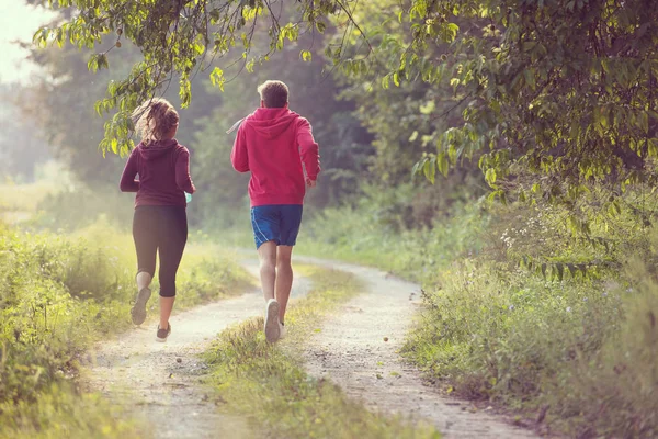 田舎道をジョギングしながら健康な生活を楽しんでいる若いカップル運動とフィットネスの概念 — ストック写真