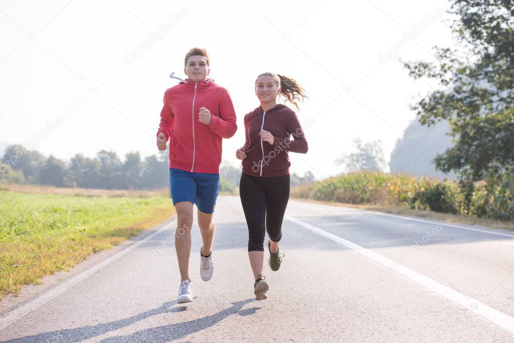 young couple enjoying in a healthy lifestyle while jogging along a country road, exercise and fitness concept