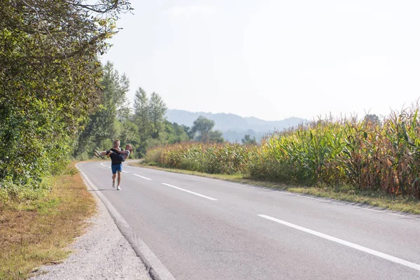 男人一边抱着一个女人一边沿着乡间小路慢跑 一边提出运动和健身的概念 — 图库照片