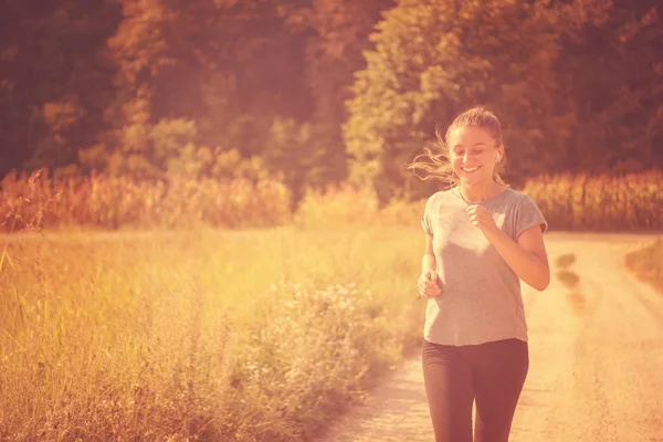 国の道路 フィットネスの概念に沿ってジョギングしながら健康的なライフ スタイルで楽しむ若い女性 — ストック写真