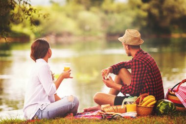 Piknik zamanı içki ve nehir kıyısında güzel doğada yiyecek zevk aşık çift