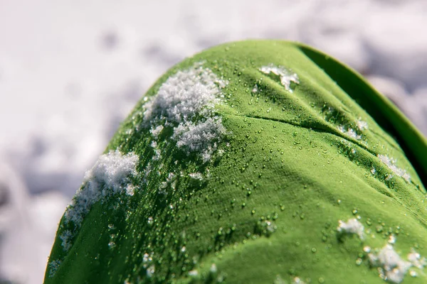冬のスキー服から緑の防水布に雪や水滴など — ストック写真