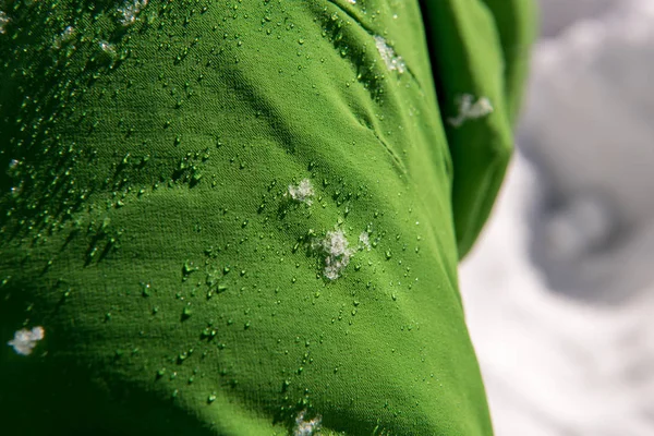 Kışın Kayak Kıyafetleri Yeşil Geçirmez Kumaş Üzerinde Kar Damlacıkları — Stok fotoğraf