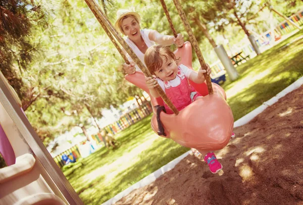 Ung Mamma Och Hennes Lilla Dotter Ler Tillsammans Medan Swinging — Stockfoto