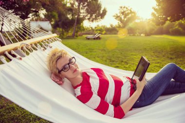 huzurlu bir bahçe hamakta üzerinde rahatlatıcı tatil sırasında bir tablet bilgisayar kullanan genç kadın