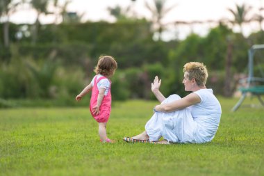 Genç Anne ve serbest zaman dışında oynarken arka bahçesinde çimenlerin üzerinde doğa kavramı içinde mutlu aile zevk şirin küçük kız