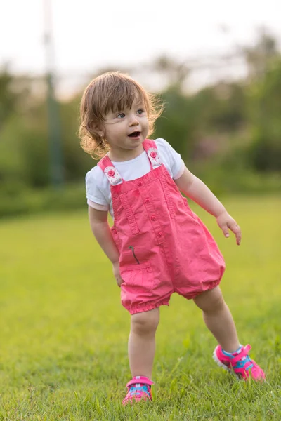 陽気ながら広々 とした裏庭の芝生の上を実行している時間を過ごす遊び心のあるかわいい女の子 — ストック写真
