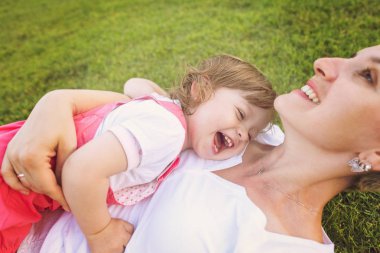 Genç Anne ve serbest zaman dışında oynarken arka bahçesinde çimenlerin üzerinde doğa kavramı içinde mutlu aile zevk şirin küçük kız