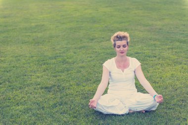 sağlıklı kadınla çimenlerin üzerinde güzel doğada meditasyon ve yoga yaparken egzersiz yaparken rahatlatıcı
