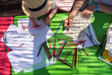 Genç Anne ve onun küçük kızı neşeyle harcama zaman içinde dış anaokulu renkli resimler çizerken kalem boya kalemleri kullanarak birlikte