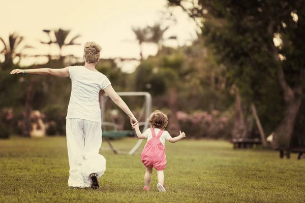 若い母親とかわいい小さな娘の裏庭の芝生の上 自然概念で幸せな家族で外で遊ぶ自由な時間を楽しんで — ストック写真