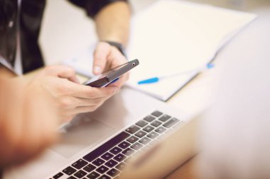 İş adamları konferans odasındaki seminer sırasında akıllı telefondan yazı yazıyor.