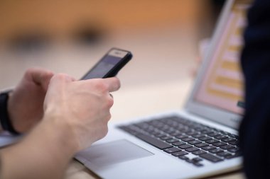 İş adamları konferans odasındaki seminer sırasında akıllı telefondan yazı yazıyor.
