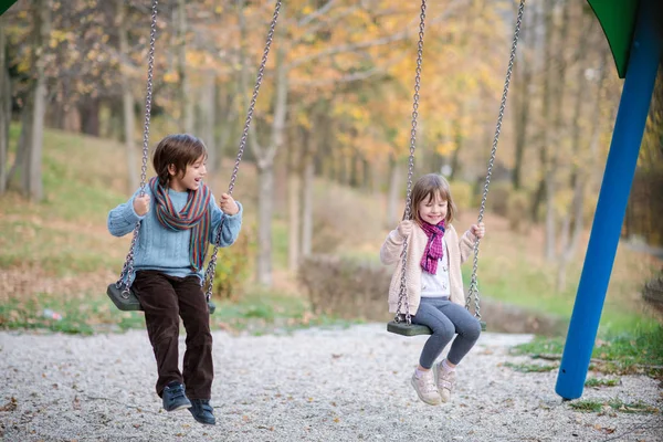 快乐的孩子们在外面玩的秋千小弟弟和妹妹很开心 — 图库照片