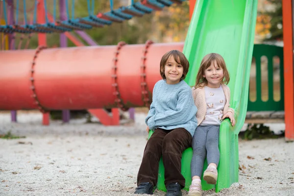 Cutte 少女と子供の少年秋曇りの日の遊び場で遊んでいる間楽しいと喜びを公園 — ストック写真