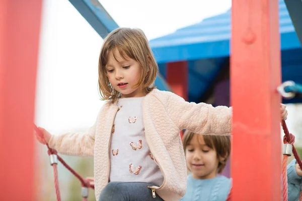 Cutte 少女と子供の少年秋曇りの日の遊び場で遊んでいる間楽しいと喜びを公園 — ストック写真