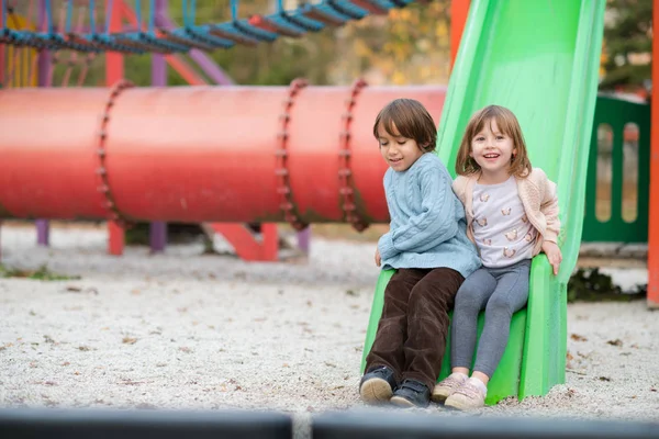 Cutte 少女と子供の少年秋曇りの日の遊び場で遊んでいる間楽しいと喜びを公園 — ストック写真