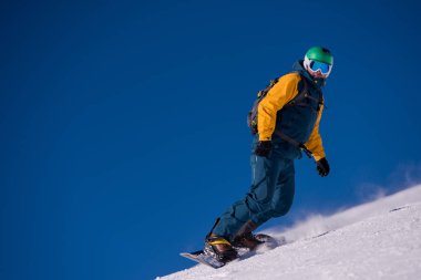 Eğim ve yolculuğu serbest stil güneşli kış gününde Alp Dağları üzerinde çalışan genç freestyle snowboard. Kış spor ve eğlence, eğlence açık hava etkinlikleri.