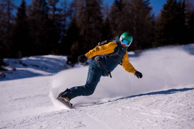 Eğim ve yolculuğu serbest stil güneşli kış gününde Alp Dağları üzerinde çalışan genç freestyle snowboard. Kış spor ve eğlence, eğlence açık hava etkinlikleri.