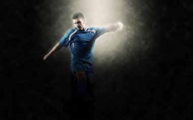 futbol oyuncusu tekme ile topu Futbol Stadyumu alanında siyah arka plan üzerine izole yapıyor