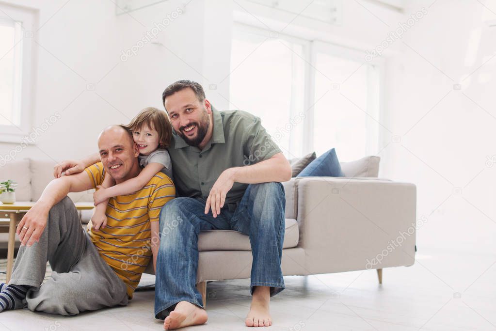 Portrait of male gay couple with adopted children little girl while having fun at home