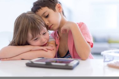 sevimli küçük kardeşim ve kız kardeşi eğleniyor evde tablet bilgisayarda oyun childrends