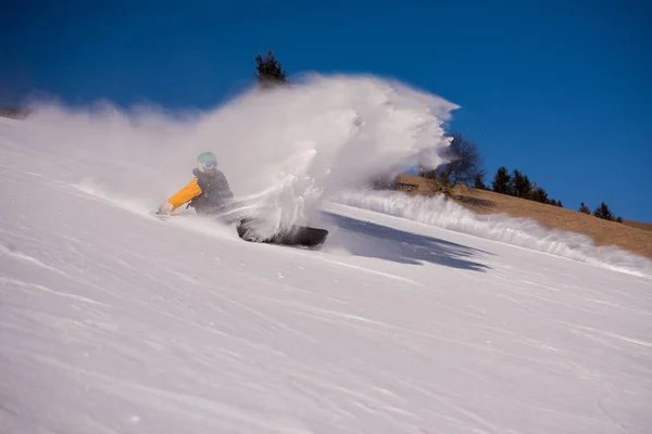フリー スタイルのスノーボーダーが雪の山を彫刻中にクラッシュしたし 彼の後ろに雪を散らし — ストック写真