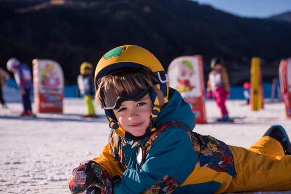 在阳光明媚的日子里 在滑雪胜地的滑雪胜地 当他躺在雪地上的时候 小男孩滑雪者在雪地上玩耍 — 图库照片