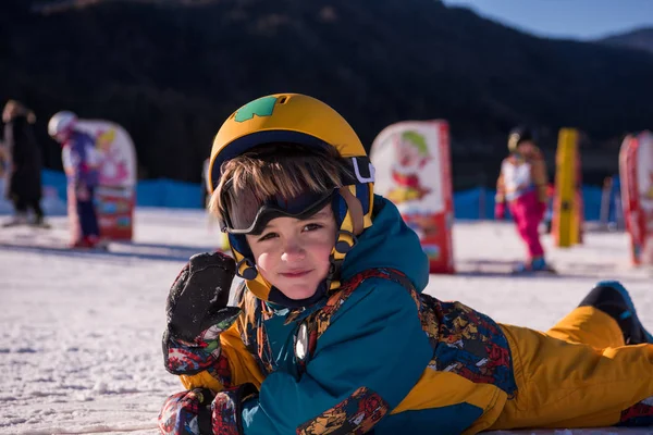 在阳光明媚的日子里 在滑雪胜地的滑雪胜地 当他躺在雪地上的时候 小男孩滑雪者在雪地上玩耍 — 图库照片
