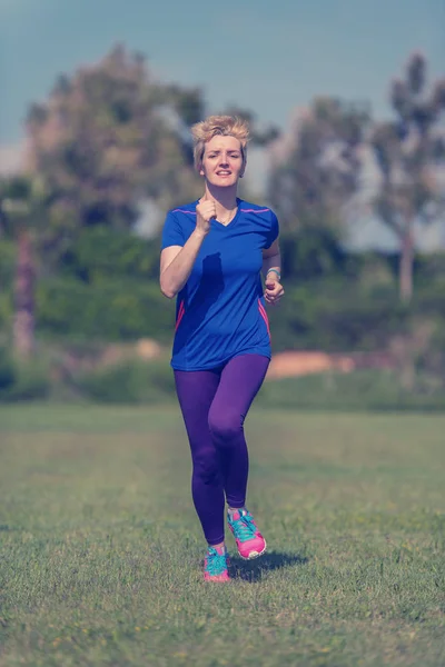 若いスポーティな女性ランナーの晴れた朝の美しい熱帯公園でマラソンのトレーニング — ストック写真