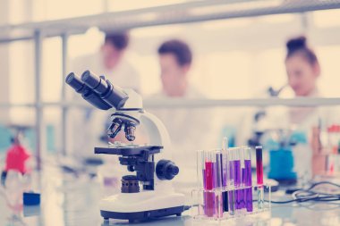 Çalışma yerindeki mikroskop farklı sıvıyla test tüplerinin yanında. Sağlık ve biyoteknoloji kavramı
