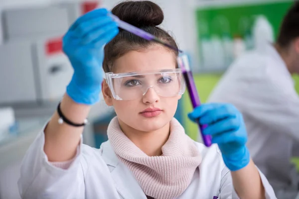 戴防护眼镜的年轻女生在明亮的实验室 教育和医学概念下进行化学实验 — 图库照片