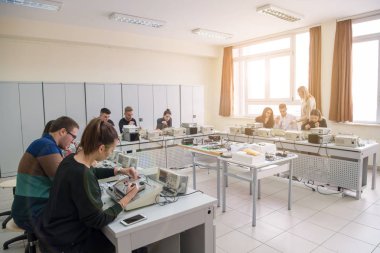 Elektronik sınıf, eğitim ve teknoloji konseptinde öğretmenle birlikte teknik meslek pratiği yapan bir grup genç öğrenci