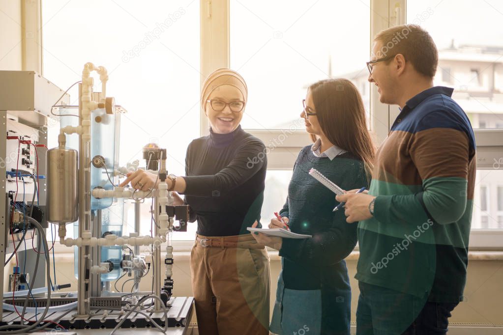 Group of students doing technical vocational practice with young female muslim teacher in the electronic classroom, Education and technology concept