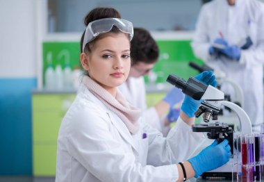 Bir grup genç tıp öğrencisi kimya laboratuarında birlikte araştırma yapıyor, üniversite öğrencilerinin kapalı alanda yaptığı takım çalışması.