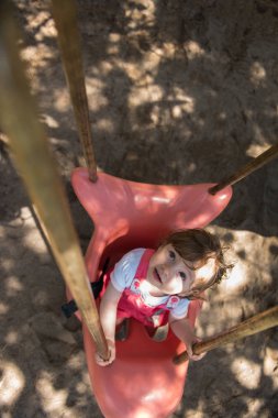 neşeli gülümseyen sevimli küçük kız parkta oyun üzerinde sallanan süre eğleniyor