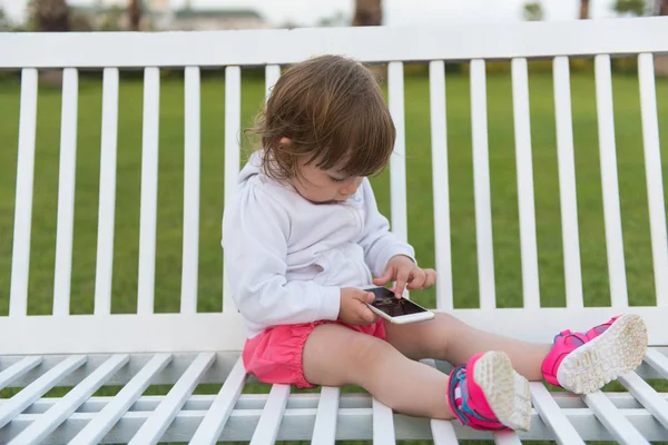 Güzel Küçük Kız Parkta Bankta Otururken Cep Telefonu Ile Oynamak — Stok fotoğraf