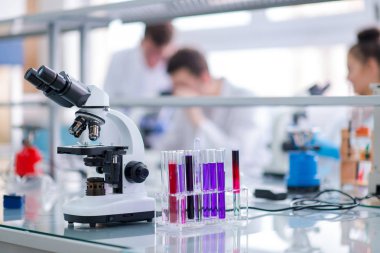 Çalışma yerindeki mikroskop farklı sıvıyla test tüplerinin yanında. Sağlık ve biyoteknoloji kavramı
