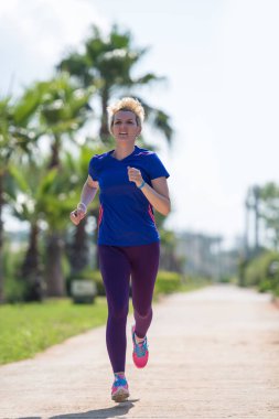 Genç sportif kadın atlet güzel tropikal Park'ta güneşli sabah çalışan maratonu için eğitim