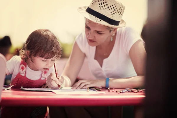 若い母親と彼女少し娘元気支出の時間外保育でカラフルな絵を描くときの鉛筆クレヨンを使って一緒に — ストック写真