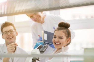 Bir grup genç tıp öğrencisi kimya laboratuarında birlikte araştırma yapıyor, üniversite öğrencilerinin kapalı alanda yaptığı takım çalışması.