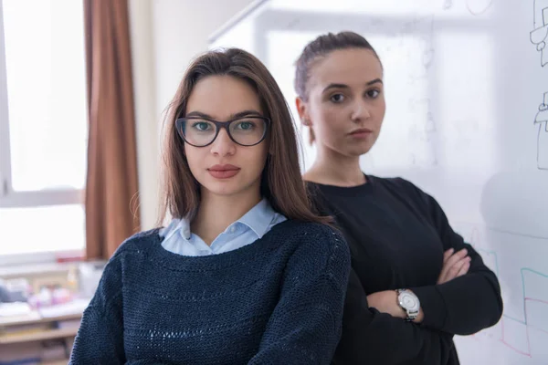 Portrait Two Young Female Students Standing Front White Chalkboard Looking — Stock Photo, Image