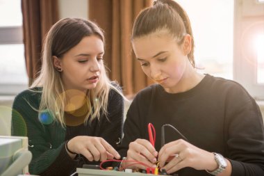 Elektronik sınıf, eğitim ve teknoloji konseptinde öğretmenle birlikte teknik meslek pratiği yapan bir grup genç öğrenci