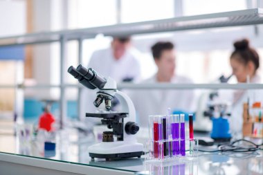 Çalışma yerindeki mikroskop farklı sıvıyla test tüplerinin yanında. Sağlık ve biyoteknoloji kavramı
