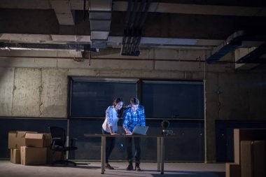 Gruptaki genç iş adamları, inşaat sahasındaki mimar ve mühendis geceleri yeni açılan ofiste dizüstü bilgisayarla belge ve iş akışını kontrol ediyorlar.