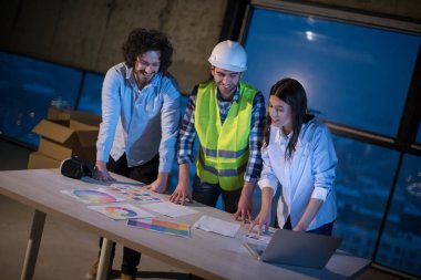 Gruptaki genç iş adamları, inşaat sahasındaki mimar ve mühendis yeni açılan ofiste dizüstü bilgisayar kullanarak belge ve iş akışını kontrol ediyorlar.