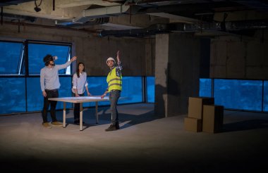 Gruptaki genç iş adamları, inşaat sahasındaki mimar ve mühendis yeni açılan ofiste dizüstü bilgisayar kullanarak belge ve iş akışını kontrol ediyorlar.