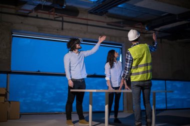 Gruptaki genç iş adamları, inşaat sahasındaki mimar ve mühendis yeni açılan ofiste dizüstü bilgisayar kullanarak belge ve iş akışını kontrol ediyorlar.