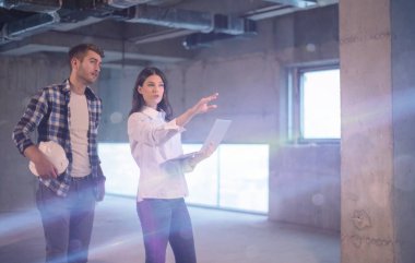 Gruptaki genç iş adamları, inşaat sahasındaki mimar ve mühendis yeni açılan ofiste dizüstü bilgisayar kullanarak belge ve iş akışını kontrol ediyorlar.