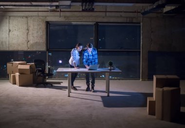 Gruptaki genç iş adamları, inşaat sahasındaki mimar ve mühendis geceleri yeni açılan ofiste dizüstü bilgisayarla belge ve iş akışını kontrol ediyorlar.